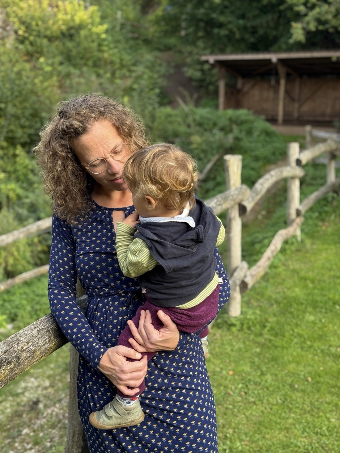 Amelie mit ihrem Kind auf dem Arm an der Weide